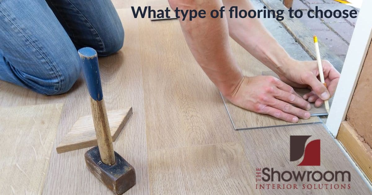 Man kneeling while measuring for a hardwood flooring installation. Flooring, hammer, pencil are also visable.